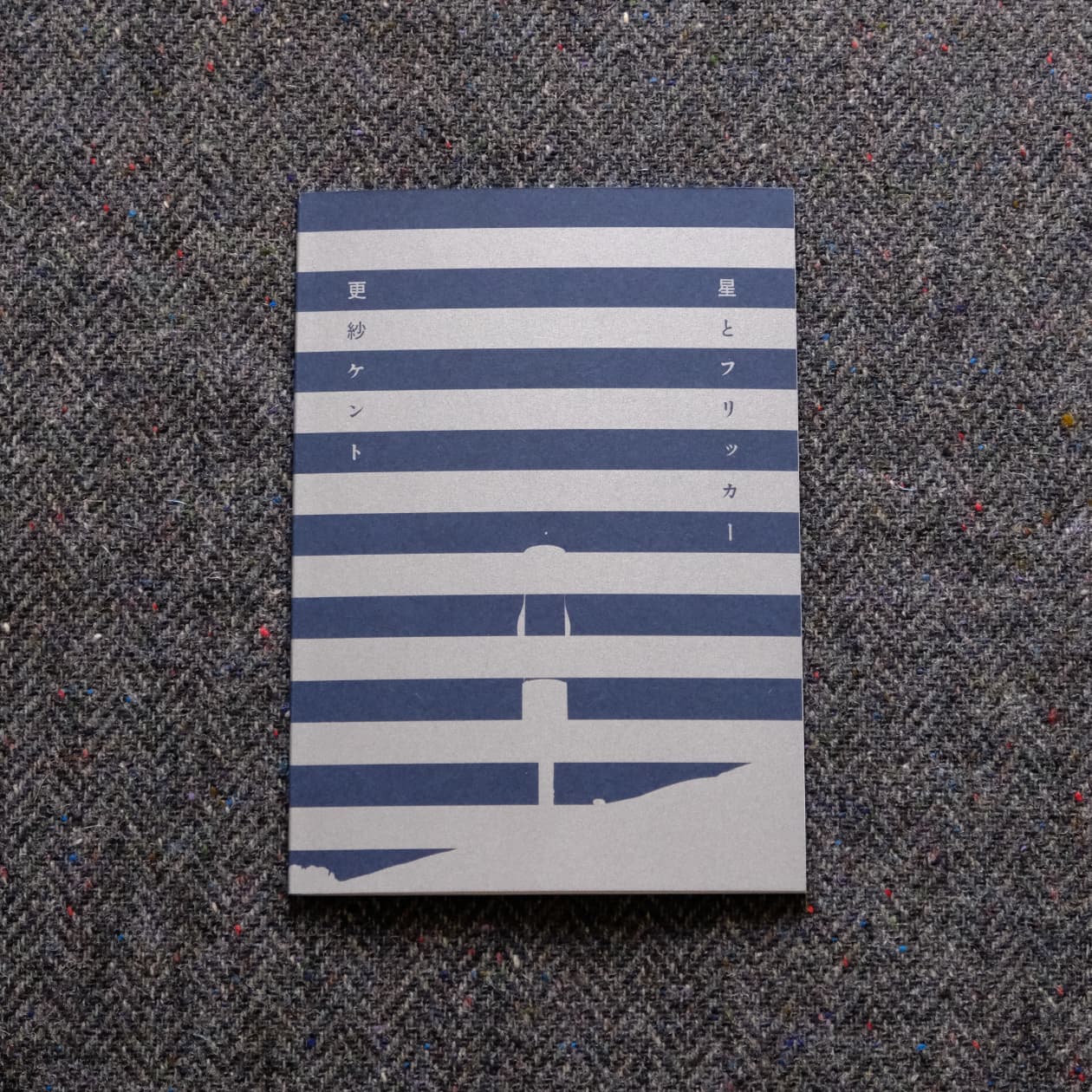 メインビジュアル。布の上に『星とフリッカー』が表紙を表にして置かれている。